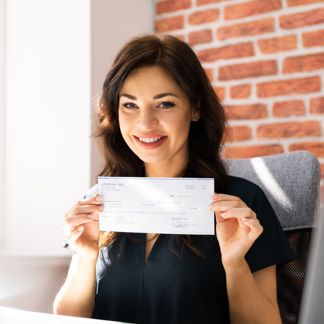 Woman joyfully holding a check.